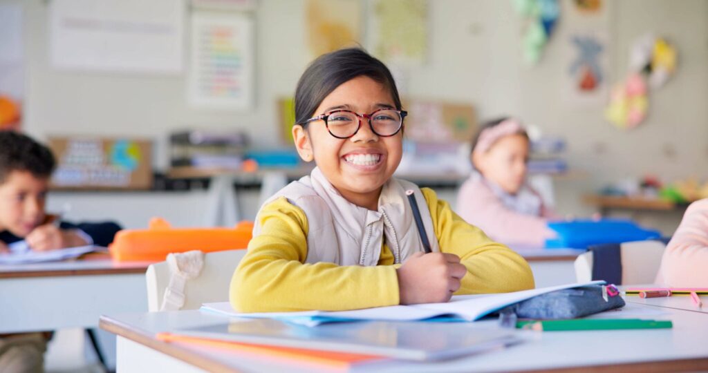 Student in school smiling at her desk