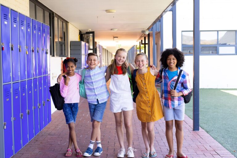 Portrait of 5 students standing in a hallway smiling