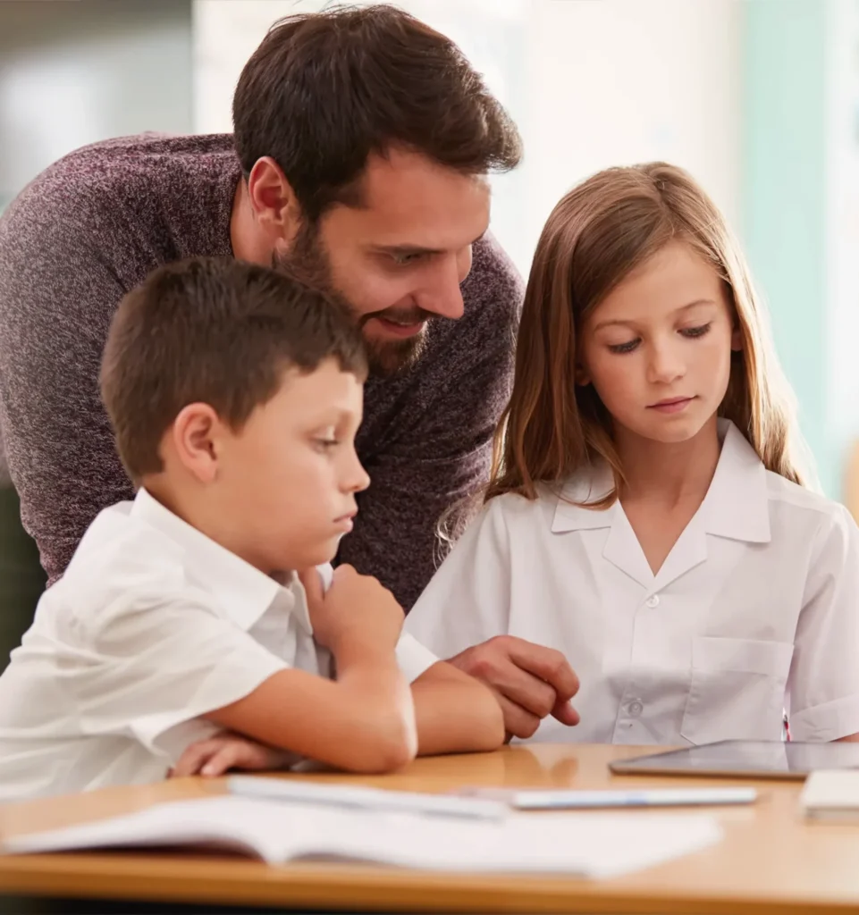 A teacher helps 3 students with a digital writing project