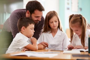 A teacher helps 3 students with a digital writing project