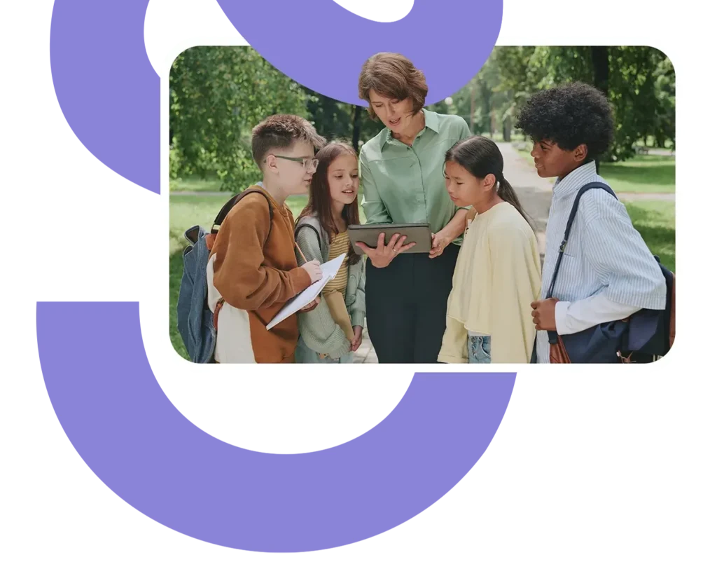 a teacher works outside on a tablet with a group of students