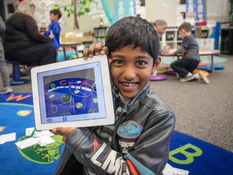 Student holding tablet smiling