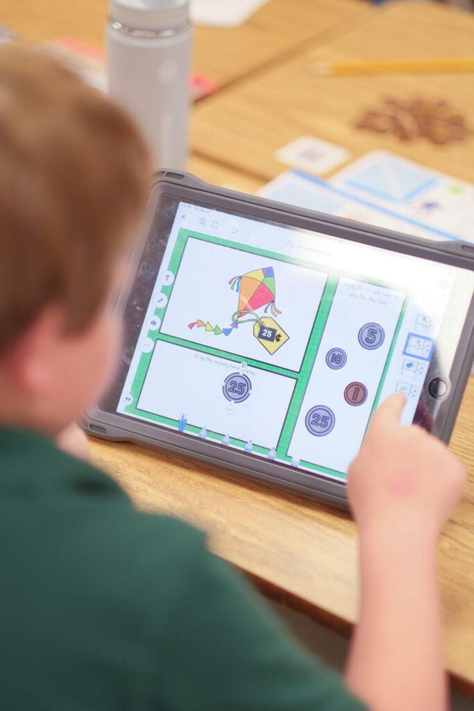 a student uses his iPad to complete a seesaw activity.