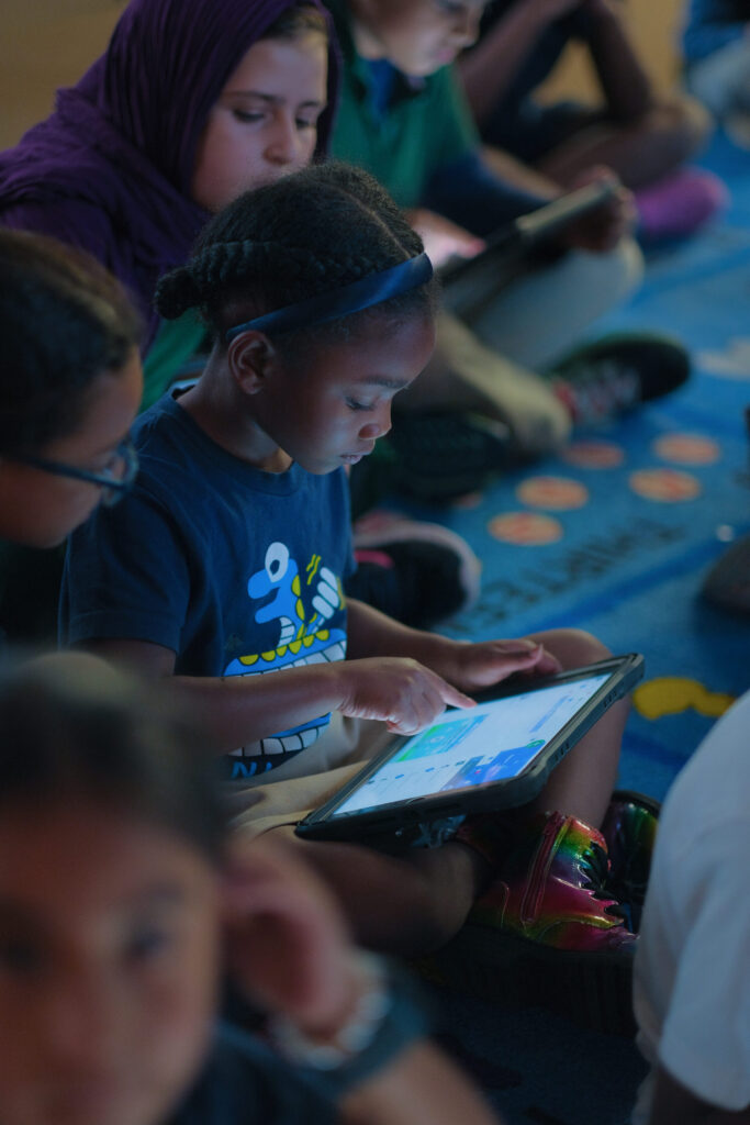 a student uses her iPad to complete a seesaw activity.