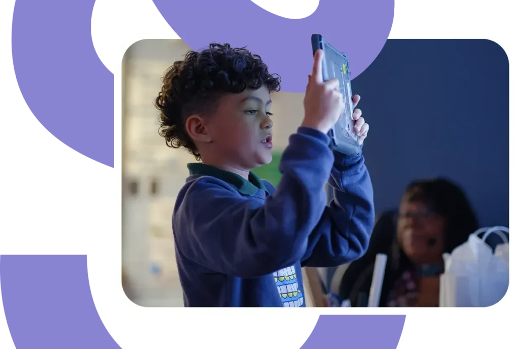 a student holds up an ipad to take a photo of his work