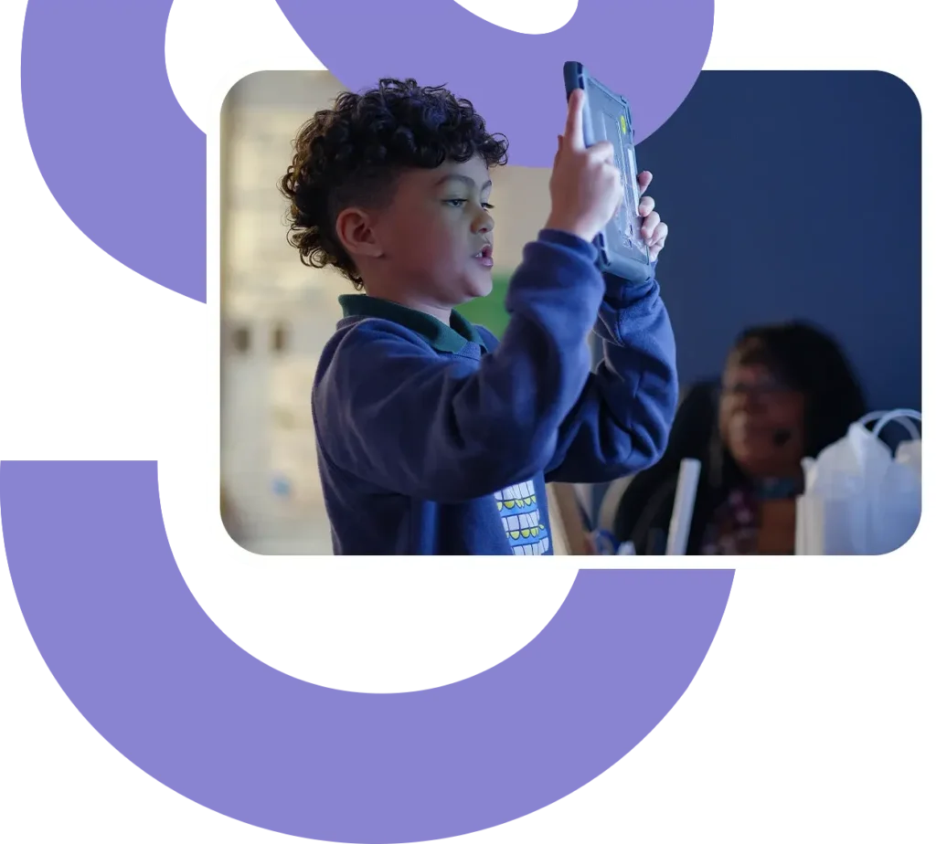 a student holds up an ipad to take a photo of his work