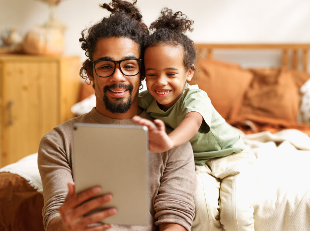 A father and child happily look at a tablet together