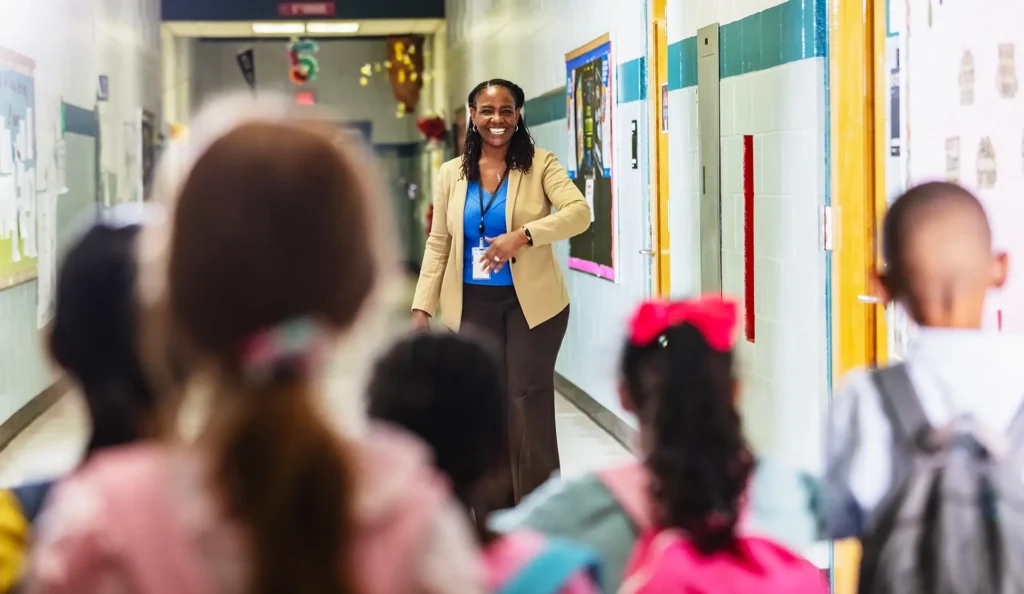 Teacher greets primary school students in the school hallway